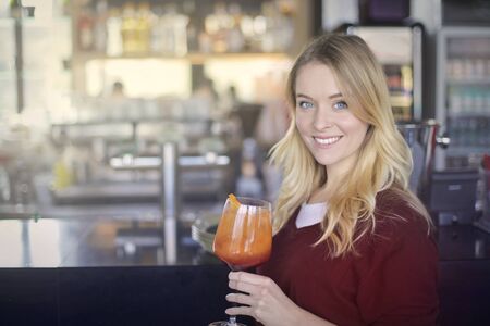 A blonde woman is drinking a cocktailの写真素材