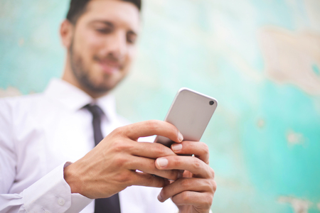 Young businessman is typing on his phoneの写真素材