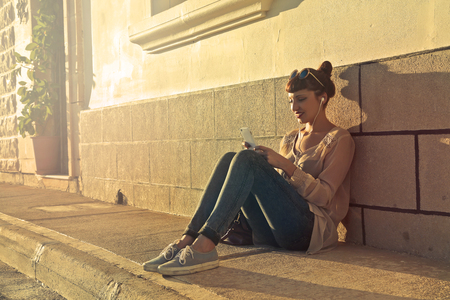 Woman is sitting on the ground on the streetの写真素材