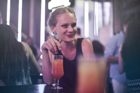 Happy girl drinking in a dance clubの写真素材