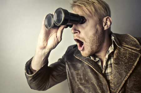 Portrait of a man looking through binocularsの写真素材