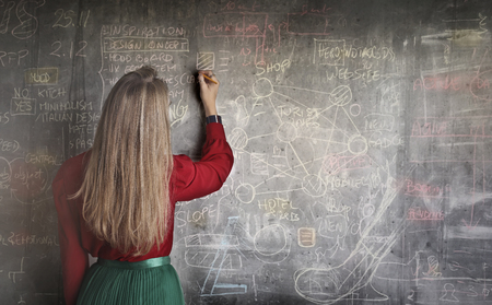 Elegant girl writing on a blackboardの写真素材