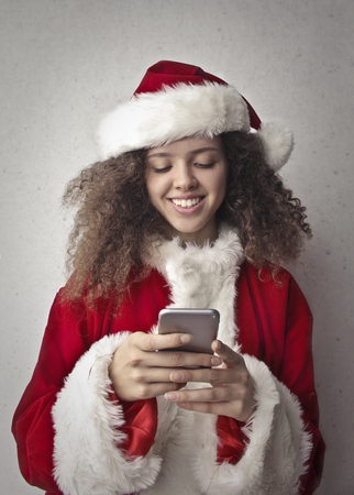 Portrait of a girl dressed as Santa Claus using a smartphoneの写真素材