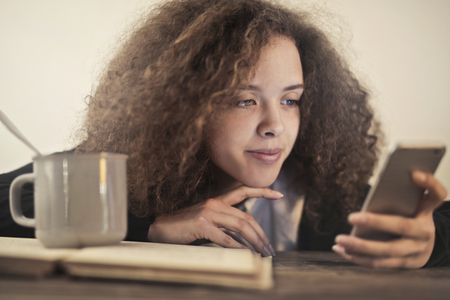 Girl with a smartphone and a cup of teaの写真素材
