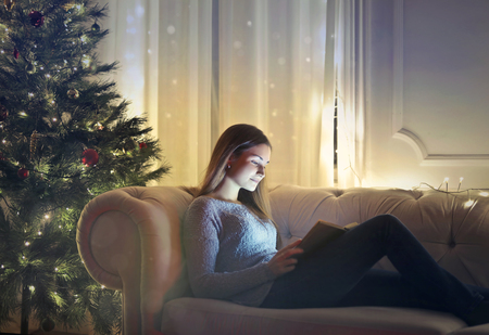 Girl eating a book on a sofaの写真素材