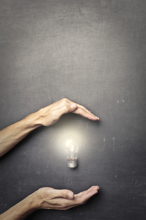 Two hands and a light bulbの写真素材