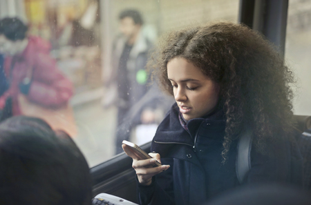 Girl using a phone on a busの写真素材