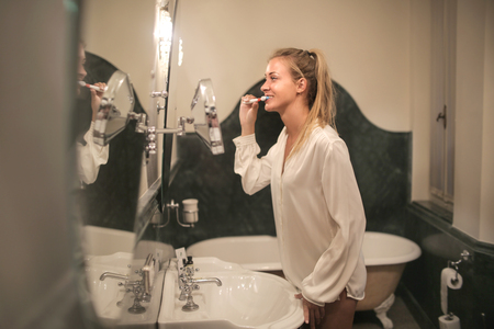 Girl brushing her teeth in a bathroomの写真素材
