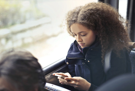 Girl using a smartphone on a busの写真素材