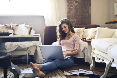 Happy girl using a laptop in a living roomの写真素材