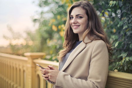 Smiling girl with a smartphone outdoorの写真素材