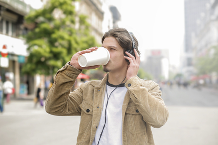 Guy listening to music and drinking outdoorの写真素材