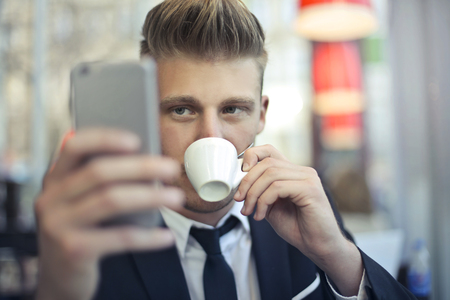 Man taking a selfie while drinking a coffeの写真素材