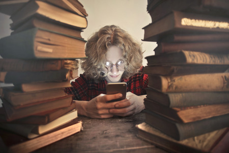 Guy with a smartphone surrounded by books
