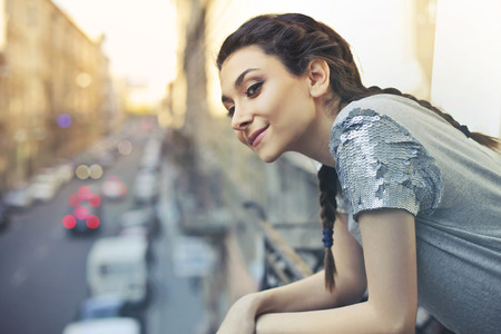 Girl looking at a city street from a balconyの写真素材