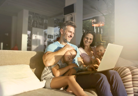 Happy family using a laptop on a sofaの写真素材