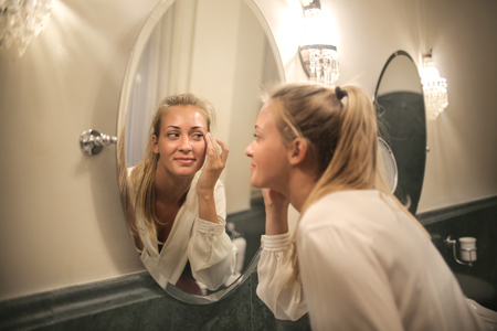 Girl looking at herself in a mirrorの写真素材
