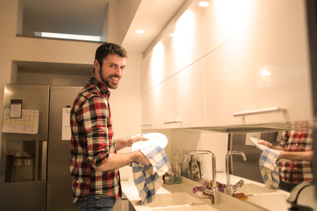 Guy drying dishes in a kitchenの写真素材