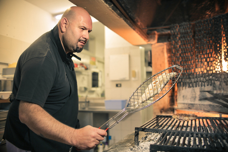 Chef cooking fish in a restaurant kitchenの写真素材