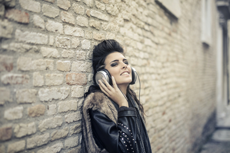 Grunge girl listening to music with headphones outdoorの写真素材