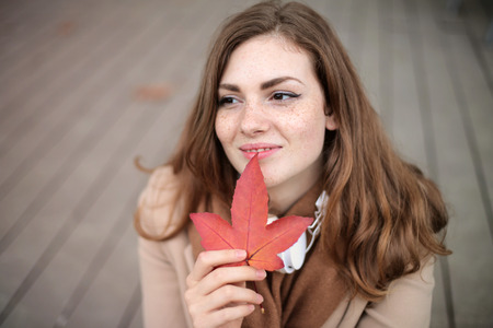 Girl holding an autumn leaveの写真素材