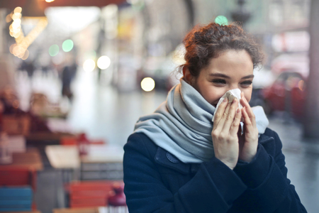 girl blowing her nose outdoorの写真素材