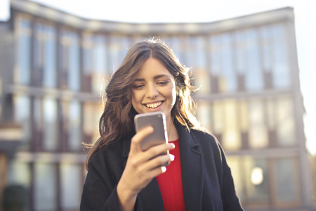 Smiling young woman using a smartphone outdoorの写真素材