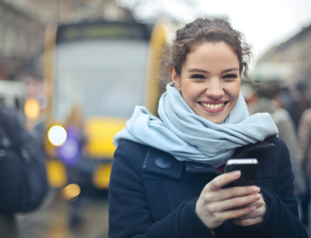 Happy girl with a smartphone outdoor in winterの写真素材