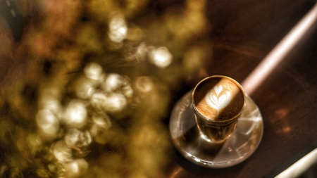 A cup of latte art with golden flowers.の素材