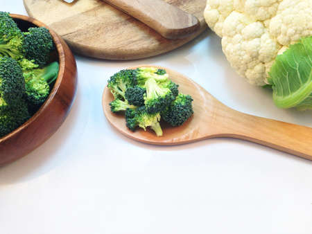 Broccoli in wooden bowl and wooden spoon on white backgroundの写真素材