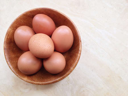 Eggs in wooden bowl on wooden backgroundの写真素材