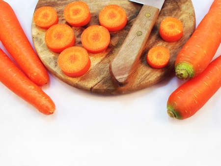 Carrot and cut pieces isolated with wooden cutting board and knife on white backgroundの写真素材