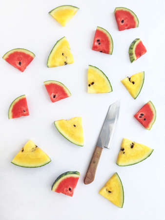 slices of red and yellow watermelon and knife on white backgroundの写真素材