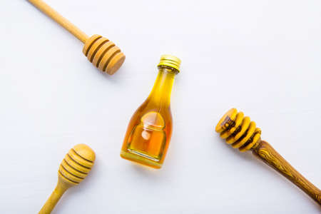 Honey wooden dipper and little honey bottle on white wooden background.の写真素材