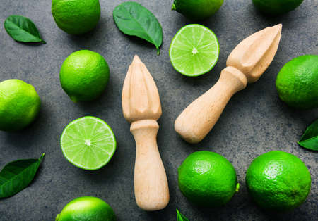 Fresh limes and wooden juicer on white background. Top view with copy spaceの写真素材