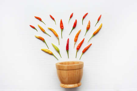 Colorful chili peppers with wooden mortar on white.の写真素材