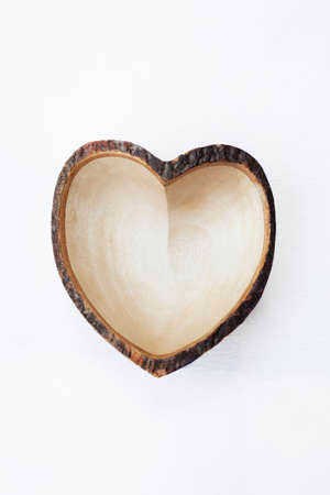 Empty wooden dish heart shape on white wooden background.の写真素材
