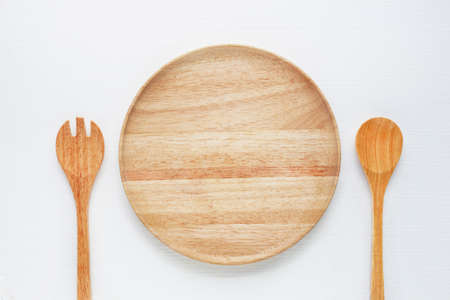 Wooden plate  with spoon and fork on white background.の写真素材