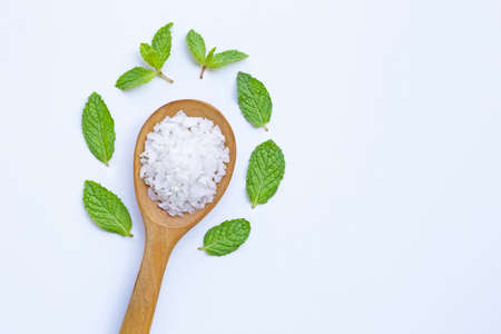 Salt in wooden spoon with fresh mint on white backgroundの写真素材