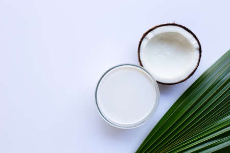 Half Coconut with glass bowl of coconut milk on white background.の写真素材