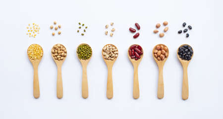 Different types of legumes on wooden spoon, white background.の写真素材