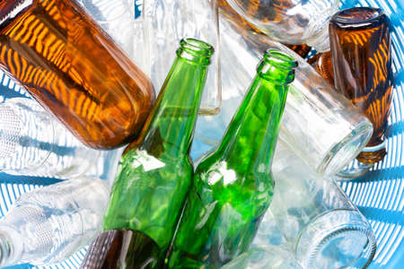 Glass bottles in blue waste basket.