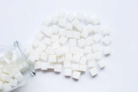 Glass bottle of sugar cubes on white background.