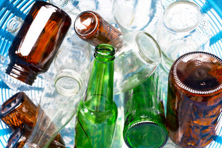 Glass bottles in blue waste basket.の写真素材