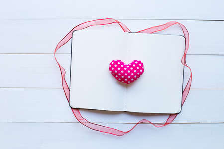 Diary notebook with valentine's hearts on white wooden background. Top view