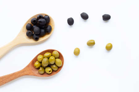 Olives on wooden spoon, white background. Top view
