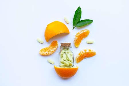 Vitamin C bottle and pills with orange fruit on white backgroundの写真素材