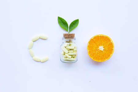 Vitamin C bottle and pills with orange fruit on white background.の写真素材