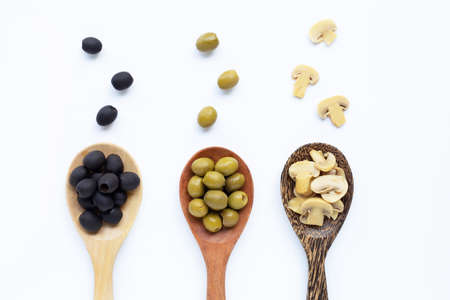 Olives and Champignon mushrooms on wooden spoon, white background.