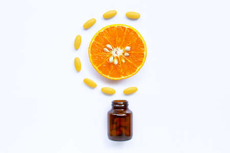 Vitamin C bottle and pills with orange fruit on white backgroundの写真素材